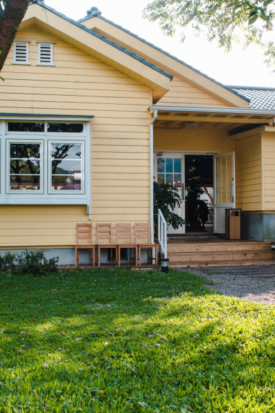 A charming yellow house with wooden windows and green grassy garden